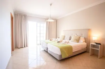 a white bedroom with a large bed and a window at Villa Cinema - Perfect Union in Albufeira