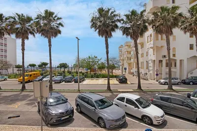 a group of cars parked in a parking lot with palm trees at T2 2 Linha Praia Vista Mar in Quarteira