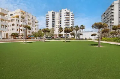 a large field of grass with buildings in the background at T2 2 Linha Praia Vista Mar in Quarteira