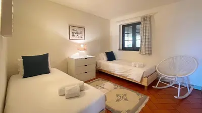 a bedroom with a bed and a chair and a window at T2 Monte Sol HsRentals Vilamoura in Vilamoura