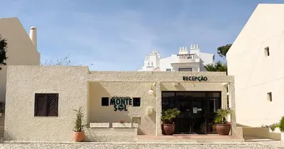 a room with two beds and a chair and a window at T2 Monte Sol HsRentals Vilamoura in Vilamoura