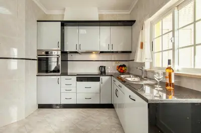 a kitchen with white cabinets and a counter with chairs at Villa Ocean by Algarve Vacation in Albufeira