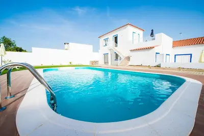 a swimming pool in front of a white house at Rosa Lilás in Boliqueime