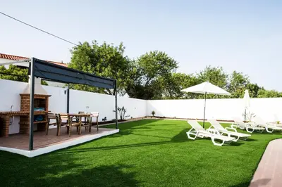 a backyard with a table and chairs and an umbrella at Rosa Lilás in Boliqueime