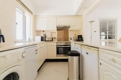 a kitchen with white cabinets and a living room at Acolhedor Apt T1, vista piscina , Balaia Golf Village in Albufeira
