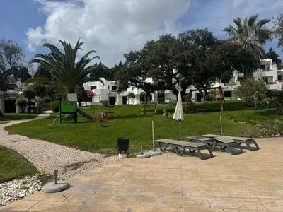 a white house with a palm tree and bushes at Acolhedor Apt T1, vista piscina , Balaia Golf Village in Albufeira