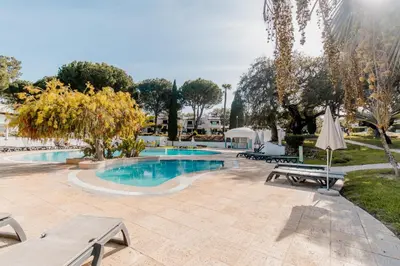 a swimming pool with a bench and an umbrella at Acolhedor Apt T1, vista piscina , Balaia Golf Village in Albufeira
