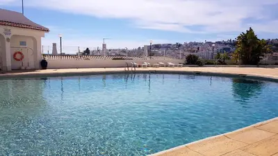 a large swimming pool with chairs and a building at Albufeira, Blue Wave Retreat 65 in Albufeira