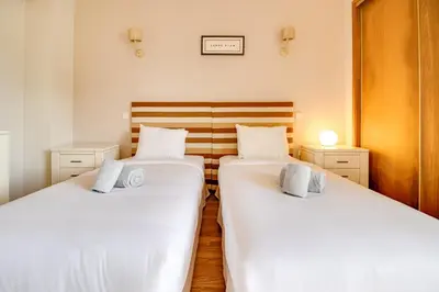 two beds in a room with white sheets at Nature Escape 2BR Villa Pool Wi-Fi AC in Olhos de Água