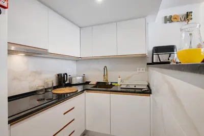 a kitchen with white cabinets and a jug of orange juice at Jungle Flat with Pool T2 Montechoro in Albufeira