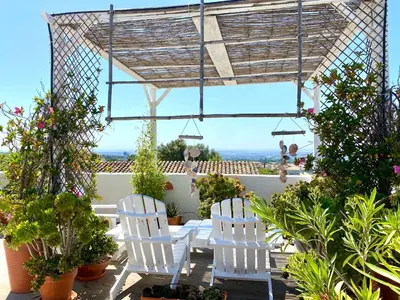 a white house with a table and a window at Casa da Aldeia in Santa Bárbara de Nexe