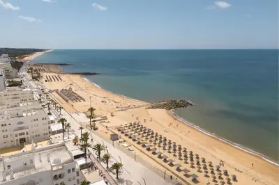 an aerial view of a beach with umbrellas and the ocean at Terracos de Quarteira II White by Real Properties in Cavacos