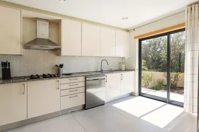 a kitchen with white cabinets and a large window at Casa Peva in Albufeira