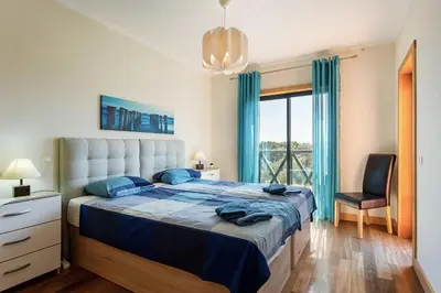 a bedroom with a large bed with blue sheets and a window at Casa Peva in Albufeira