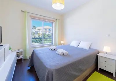 a bedroom with two towels on a bed with a window at Medronheira - Apt 1A by HelloVacations in Albufeira
