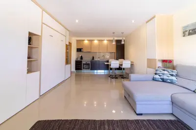 a living room with a couch and a kitchen at Medronheira - Apt 1A by HelloVacations in Albufeira