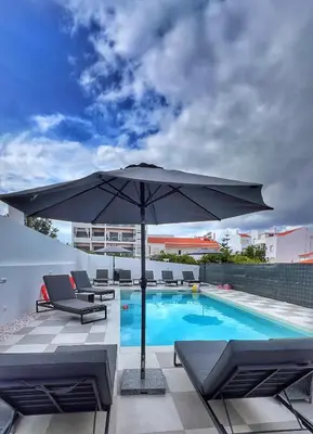 a patio with an umbrella and a swimming pool at Orange Boutique Residence - Casa Farol Adults Only in Quarteira