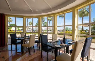 a dining room with tables and chairs and windows at Hotel Vila Galé Cerro Alagoa in Albufeira
