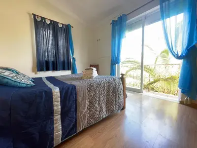 a bedroom with a bed with blue curtains and a large window at Villa Ana in Albufeira