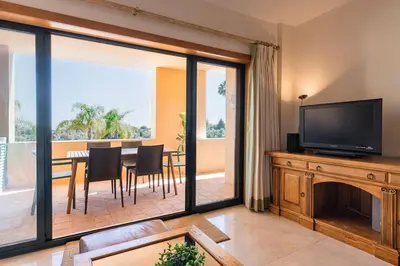 a living room with a television and a table with chairs at Vilamoura Residence in Quarteira