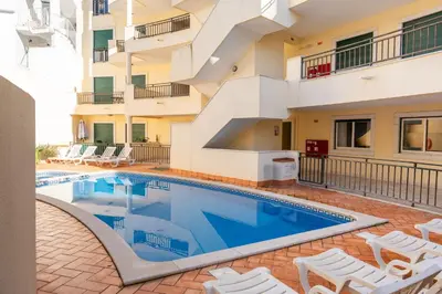 a swimming pool with chairs and a building at Old Town Boho Seaview Elegance in Albufeira