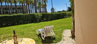 a white chair sitting next to a table with a bottle of wine at Sao Rafael Village 2 Bedroom with a Pool in Albufeira