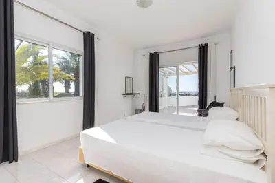 a white bedroom with a large bed and large windows at Casa Sonhos in Albufeira