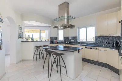 a kitchen with white cabinets and a island with bar stools at Casa Sonhos in Albufeira