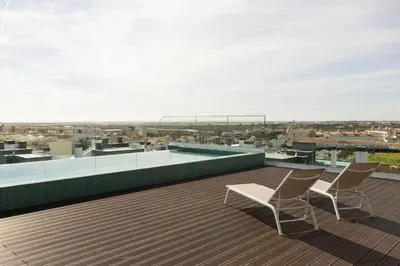 a rooftop deck with two chairs and a swimming pool at TAC - Alma Apartment in Faro