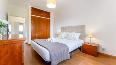 a bedroom with a white bed and a wooden floor at Sunny 3BDR Apt with Pool in Ferreiras by LovelyStay in Albufeira
