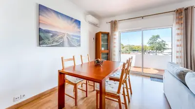 a dining room with a wooden table and chairs at Sunny 3BDR Apt with Pool in Ferreiras by LovelyStay in Albufeira