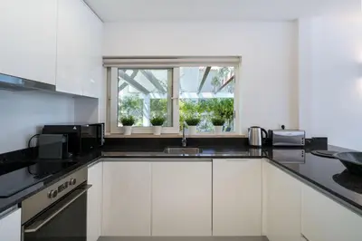a kitchen with white cabinets and a window with potted plants at Villa Celeste by SAPvillas in Vilamoura