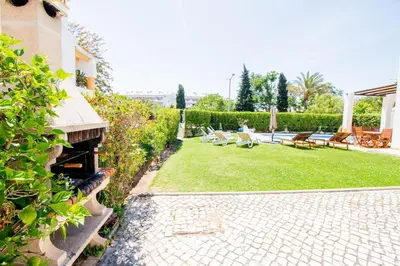 a backyard with a patio and a grass yard at Vila Anna in Albufeira