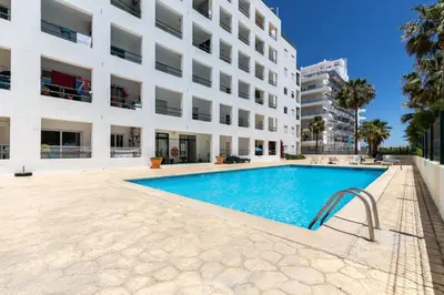 a swimming pool in front of a building at Quarteira First Line Front Beach Pool Flat View in Quarteira