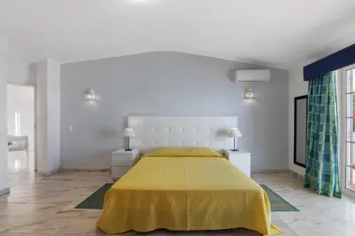 a bedroom with a large bed with a yellow bedspread at Villa Rebelo in Albufeira