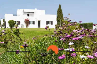 a field of flowers with a white house in the background at #293 Clube Albufeira 309 by Home Holidays in Albufeira