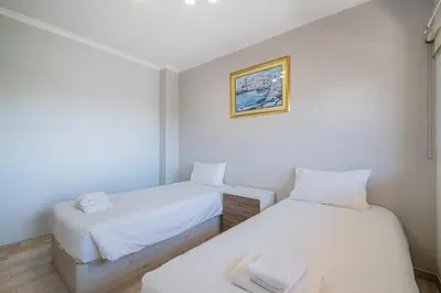 two beds in a room with white walls at Azinhais Apartment - Heart of Oura in Albufeira