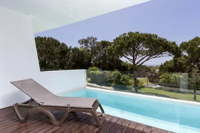 a chair sitting on a deck next to a swimming pool at Sunny Lounge Apartment in Vale do Lobo