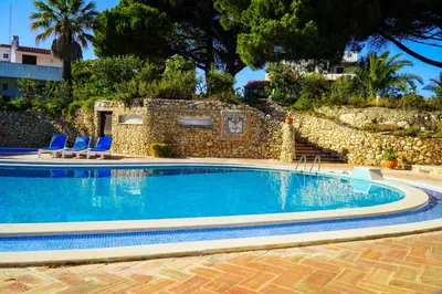 a swimming pool with blue chairs and a stone wall at Stanchion Apartment in Albufeira