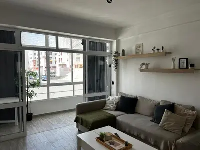 a living room with a couch and a large window at Quarteira Beach Home Haven in Quarteira