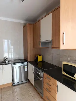a kitchen with wooden cabinets and stainless steel appliances at Casa Gomez A in Albufeira