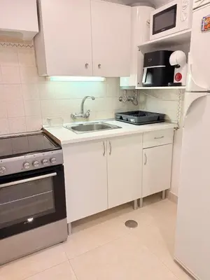 a kitchen with white cabinets and a sink and a refrigerator at OuraFlats in Albufeira