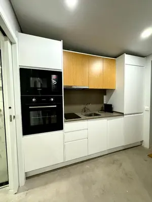 a kitchen with white cabinets and a black appliance at Acoteias Cosy Studio in Albufeira