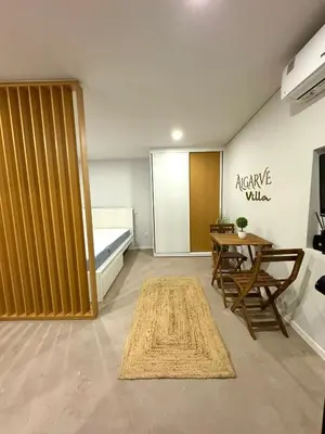 a living room with a bed and a table and a room with a tablektop at Acoteias Cosy Studio in Albufeira