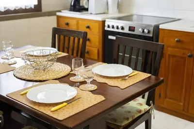 a kitchen with a wooden table with plates and wine glasses at Vila de Santa EulAlia III - Albufeira in Albufeira