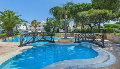 a swimming pool with a bridge in a resort at Balaia Golf Village T2 a 10 minutos da praia in Olhos de Água