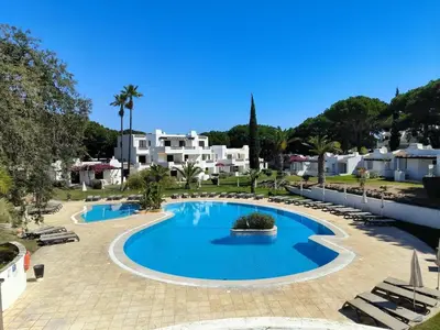 a swimming pool in a resort with buildings in the background at Balaia Golf Village T2 a 10 minutos da praia in Olhos de Água