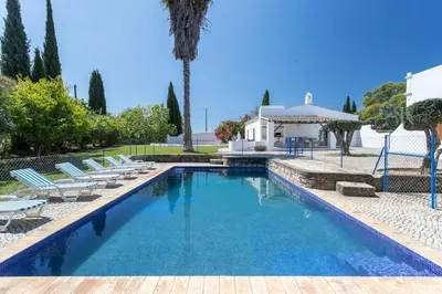 a swimming pool with lounge chairs and a house at True Local Village in Loulé