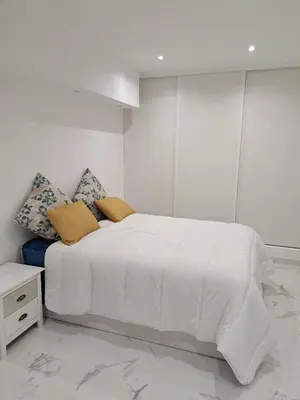 a white bedroom with a large white bed with pillows at Apartamento T1 a 10m da praia Quarteira in Quarteira