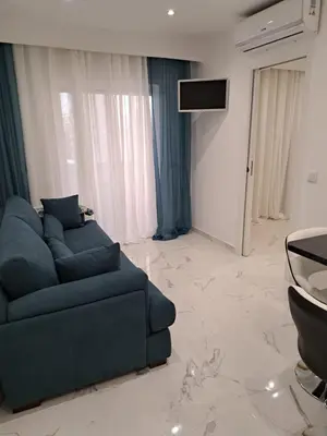 a living room with a blue couch and a tv at Apartamento T1 a 10m da praia Quarteira in Quarteira